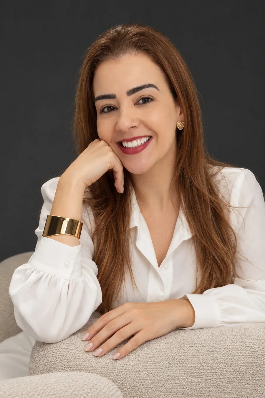 Dra. Sandra Braga, de blusa branca, apoiada em um sofá bege